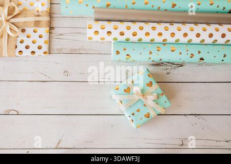 Assorted gift boxes and decorative wrapping paper rolls on rustic wood background. Trendy and cozy flat lay for holiday packaging, DIY gift wrap and c Stock Photo