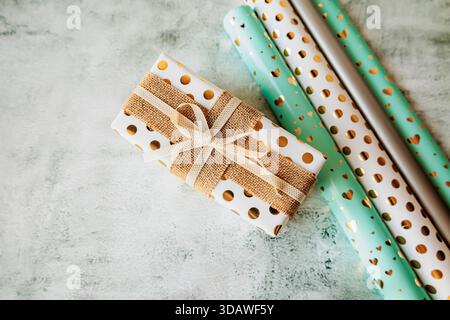 Elegant pastel wrapping paper rolls and handmade gift boxes with bows on concrete texture. Modern aesthetic perfect for online shops, tutorials, and c Stock Photo