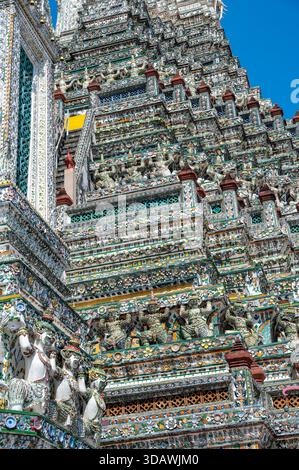 Detailed view of the ornate towers of Wat Arun in Bangkok, Thailand, showcasing rich ceramic floral patterns, sculpted figures, and intricate decorati Stock Photo