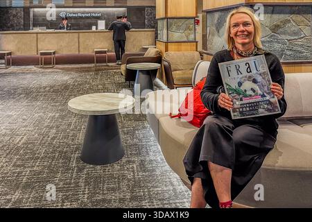 Angela Berg sits smiling on a sofa in the lobby of the Daiwa Roynet Hotel Wakayama, Japan, holding up a copy of the Japanese lifestyle magazine "FRAU" with a panda on its cover. The title, German for "woman," was chosen in the early 1990s to evoke an intellectual, European image, and the magazine targets women in their mid-twenties to early thirties; this issue features Wakayama Prefecture as a sustainable travel destination. Stock Photo