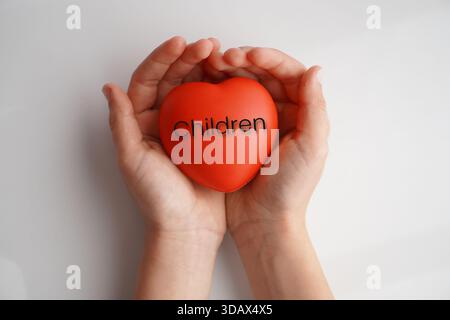 Children. A child's hands holding a red heart with the word written on it. Stock Photo