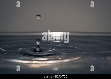 Closeup of ripples and reflections on dark water surface, creating a subtle abstract texture with soft circular waves. Stock Photo