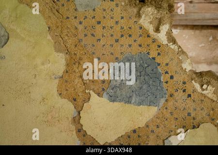 Peeling and cracked old wall layers revealing underlying plaster and faded paint patterns. Stock Photo