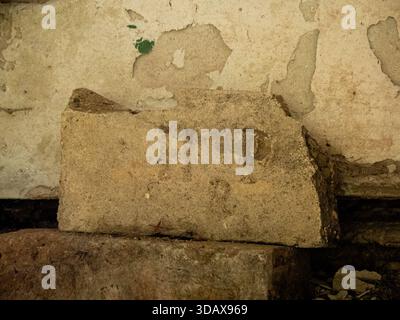 Old weathered brick against a peeling plaster wall inside an abandoned building Stock Photo