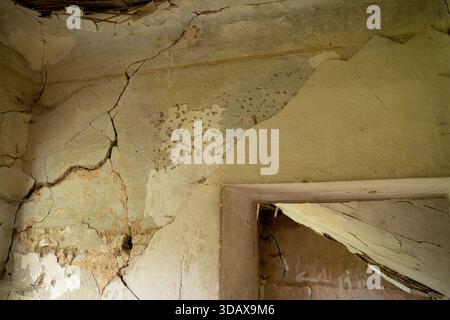 Cracked plaster wall and damaged doorway inside an abandoned building interior Stock Photo