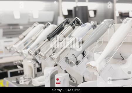 Display of multiple immersion blenders in an appliance store. Various kitchen hand blenders arranged on a shelf for demonstration. Stock Photo