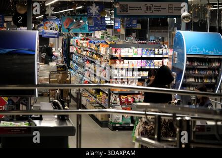 Shoppers browse a vibrant aisle with snacks and drinks during a bustling evening. Kyiv, Ukraine. December 12, 2025. Stock Photo