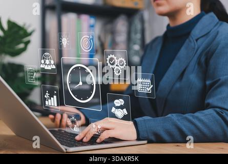 Businessperson working on laptop with icons of clock, checklist, calendar, and productivity metrics. Concept of time management, scheduling, project, Stock Photo