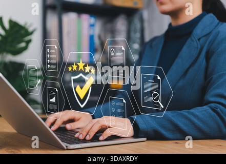 Quality Assurance and Compliance Concept. Businesswoman using laptop with icon representing quality control, document verification, audit, certificate Stock Photo