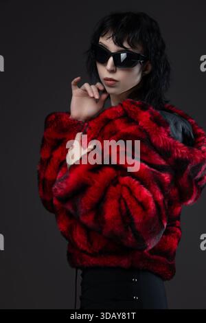 Kitsch fashion: black-haired woman in vibrant shaggy fur coat on neutral gray Stock Photo