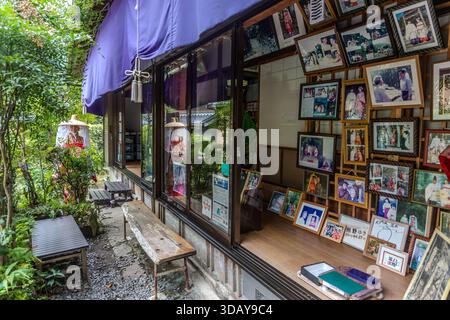 A shop for the Heian-period kimono experience stands on the Daimon-zaka section of the Kumano Kodo pilgrimage route in Nachikatsuura, Wakayama Prefecture, Japan. Framed photographs of past customers line the shop wall beside a dressed kimono display. Stock Photo