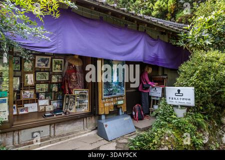 Heian Kimono Rental at Nachi-Katsuura. Women and men can dress up in Heian period clothing and walk the historic pilgrimage route up to Nachi Taisha Shrine in kimonos. Woman stamps a souvenir in a shop for rental kimonos in Nachikatsuura, Wakayama Prefecture, Japan Stock Photo