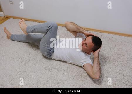 man man wear sports clothes doing abdominal abs exercises at floor, pump press warm up train at sunrise sun over sea beach outdoor on pier seaside in summer day morning. High quality Stock Photo
