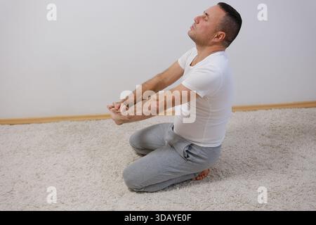 yoga man practicing variation, kneeling back bending asana. One hand up. Yoga retreat. Self care concept. Thomas beach, Bali, Indonesia. High quality photo Stock Photo