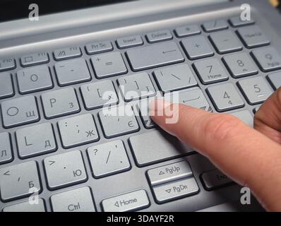 close up of finger pressing grey laptop keyboard key with cyrillic and latin layout Stock Photo