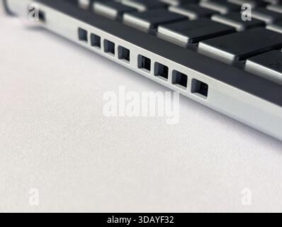 side view of modern gray laptop keyboard with aluminum body and speaker grille on white background Stock Photo