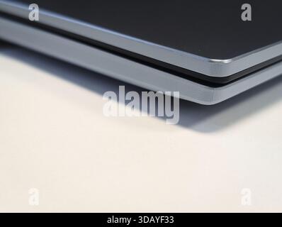 close up of the sleek, minimalist corner of a closed modern laptop on a white desk Stock Photo