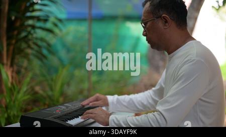 Peaceful Garden Serenity Older Mans Concentration On Black Keyboard, Soft Light White Shirt Stock Photo