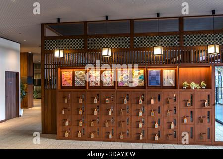 Rows of wooden lockers hold folded yukata robes in various sizes for guests of a traditional Japanese hotel with hot-spring baths (onsen) in Nachikatsuura, Wakayama Prefecture, Japan. Stock Photo