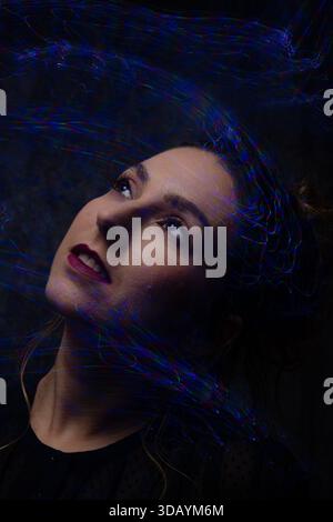 Woman light painting portrait looking up with abstract trails Stock Photo