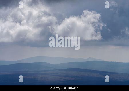Dramatic cumulus cloud deck above layered Green Mountain ridges seen from Mount Equinox, VT, USA, with distant blue haze and shifting shadows. Stock Photo