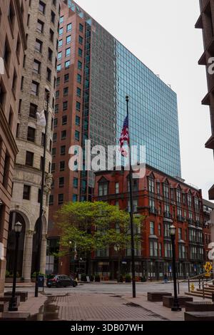 Tall modern glass building rising above historic downtown street Stock Photo