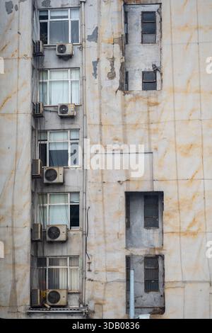 Weathered old apartment building facade with multiple air conditioning units and dirty windows showing urban decay and neglect in Istanbul Turkey arch Stock Photo