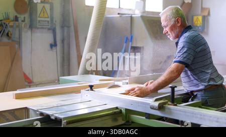 Senior carpenter working with circular saw in workshop Stock Photo