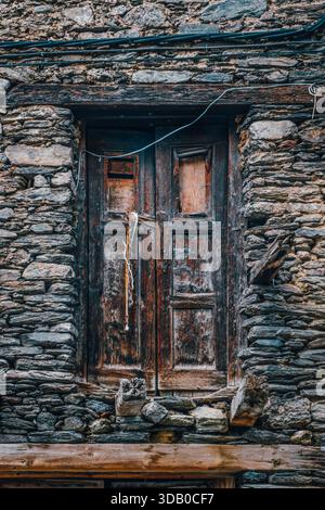 Old Weathered Wooden Door in Rough Stone Wall Texture Detail Stock Photo