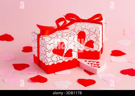 Valentine's day gift boxes with heart shaped pattern, small pink, red and white hearts on pink background. Stock Photo