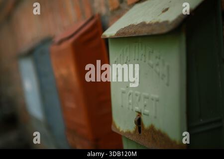 Old metal mailboxes on a brick wall, one Russian "For letters and newspapers," display weathered texture and rustic urban charm. Stock Photo