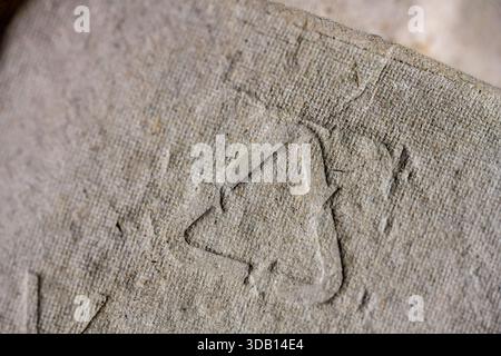 Close-up of embossed recycling symbol on cardboard. Close-up shot of an embossed recycling symbol on a cardboard surface, highlighting sustainable pac Stock Photo