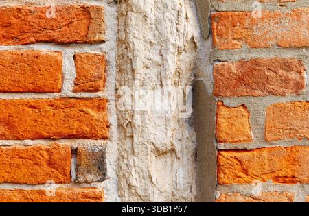 Close-up of weathered red brick wall with exposed mortar. Stock Photo
