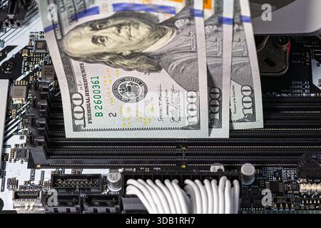 Hands in black gloves inserting 100-dollar bills into empty RAM slots on a motherboard. Conceptual image representing rising tech expenses, costly PC Stock Photo