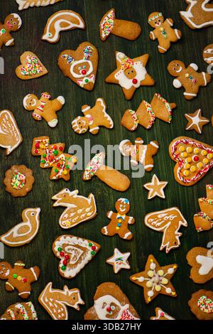 Decorative icing forms intricate seasonal motifs. Bright sprinkles enhance cheerful holiday theme. Rustic gingerbread cookie collection. Stock Photo