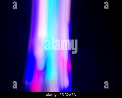 Glowing neon tones flow through smooth gradients with soft blurred motion. Abstract colorful light motion. Stock Photo