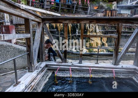 A woman cooking tamago onsen at the yuzutsu (public cooking area) in the centre of Yunomine Onsen. People have been using the hot springs for cooking since at least the Edo period (1603 to 1868). Tanabe, Wakayama Prefecture, Japan Stock Photo