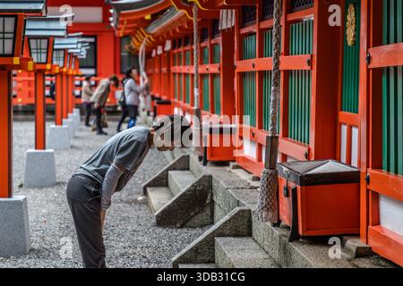 A pilgrim bows deeply in front of the shrine hall of Kumano Hayatama Taisha in Shingū, Wakayama Prefecture. The shrine is one of the three Grand Kumano Shrines (Kumano Sanzan), alongside Kumano Hongū Taisha and Kumano Nachi Taisha, and part of the UNESCO World Heritage Site "Sacred Sites and Pilgrimage Routes in the Kii Mountain Range" since 2004. Stock Photo