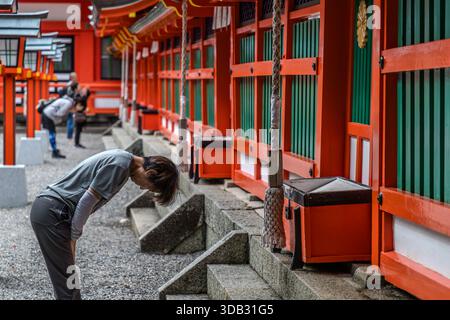 A pilgrim bows in front of the shrine hall of Kumano Hayatama Taisha in Shingū, Wakayama Prefecture. The shrine is one of the three Grand Kumano Shrines (Kumano Sanzan), alongside Kumano Hongū Taisha and Kumano Nachi Taisha, and part of the UNESCO World Heritage Site "Sacred Sites and Pilgrimage Routes in the Kii Mountain Range" since 2004. Stock Photo