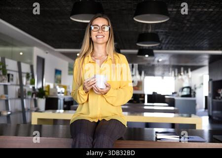 Happy young business professional woman in glasses enjoying coffee break Stock Photo