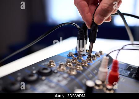 Fitting cables into professional studio gear, Attaching connectors carefully on live music setup, Ensuring accurate cable connections on audio Stock Photo