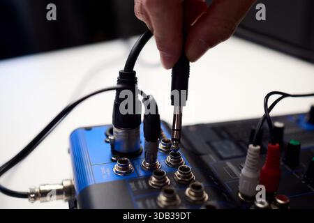 Fitting cables into professional studio gear, Attaching connectors carefully on live music setup, Ensuring accurate cable connections on audio Stock Photo