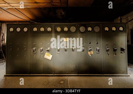 Vintage industrial electrical switchboard with analog meters and lockout tags in abandoned factory Stock Photo