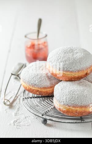 Sweet donuts with white icing on cooling grate on white table Stock Photo