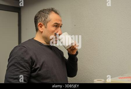 Man drinking from a white mug, pausing and thinking during a work break Stock Photo