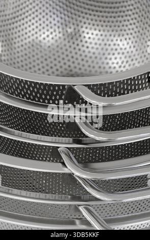 Group of round stainless steel collanders, various sizes, empty and clean, close-up shot, abstract background Stock Photo