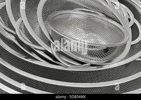 Group of round stainless steel collanders, various sizes, empty and clean, close-up shot, abstract background Stock Photo