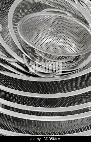 Group of round stainless steel collanders, various sizes, empty and clean, close-up shot, abstract background Stock Photo
