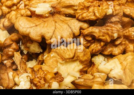 Halves of walnut kernels are arranged together at a market stall in the afternoon, showing their hard shells and inner pieces. Stock Photo