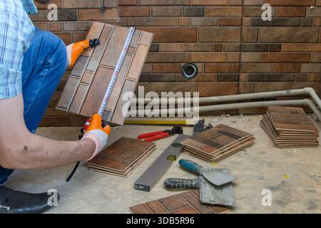 in hands to measure ceramic tile with measuring tape, construction work with ceramic tile Stock Photo